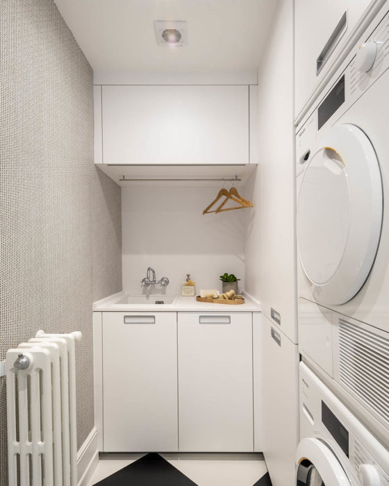 Espacio de lavandería con mobiliario blanco y organizado